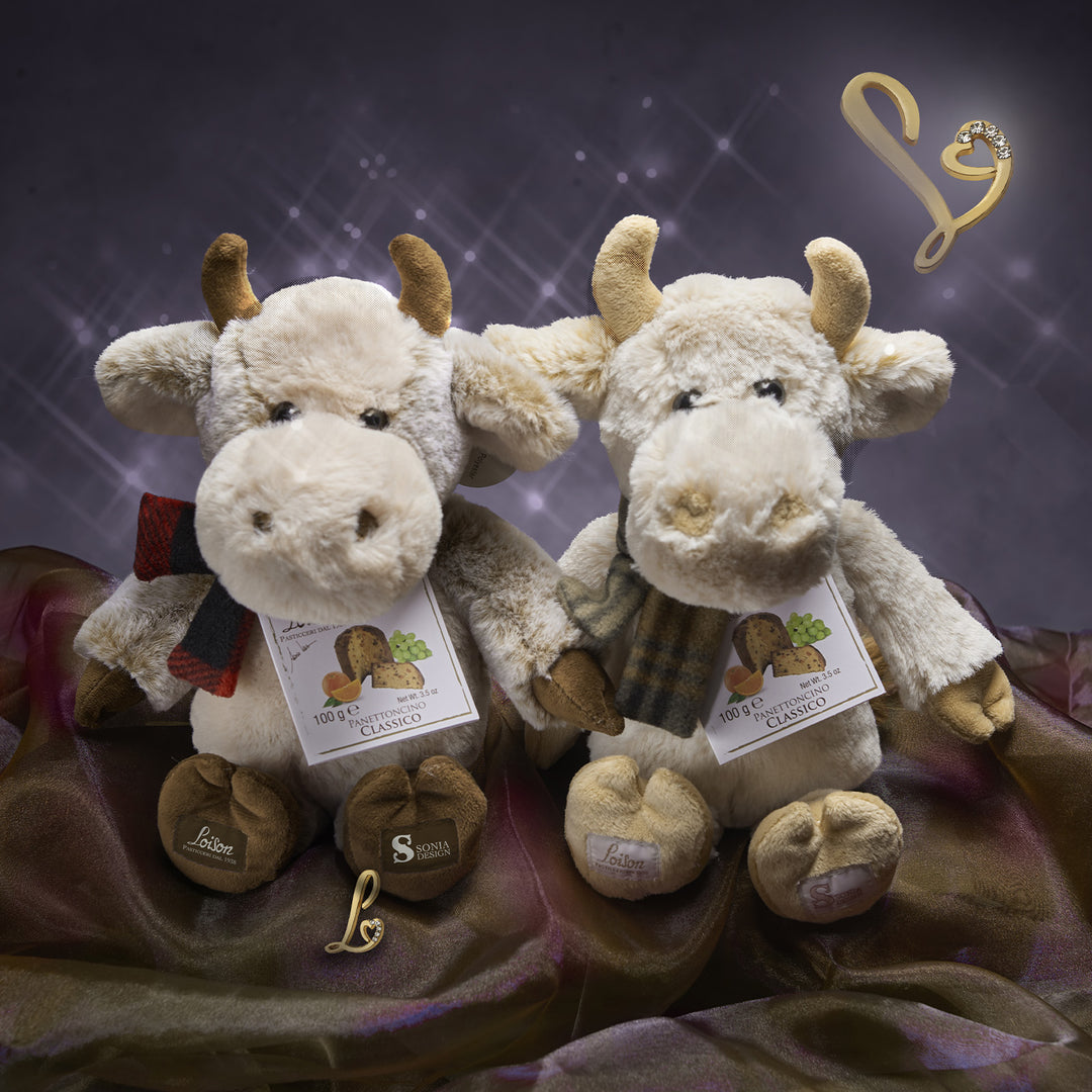 Two plush cow toys with tags on a dark background