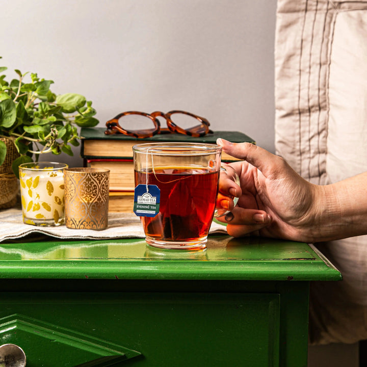 Delikatesi i tako to... Ahmad Tea decaffeinated evening tea in a glass mug on a green table with books and candles