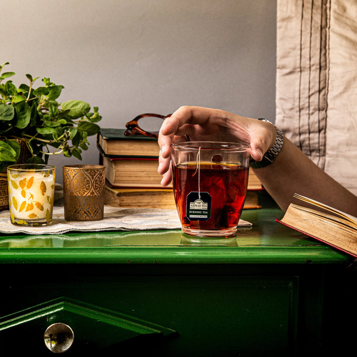 Delikatesi i tako to... Ahmad Tea decaffeinated evening tea in a glass cup on a green table with books and candles