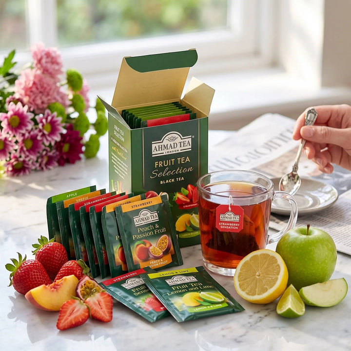 Delikatesi i tako to... Ahmad Tea fruit tea selection box with assorted tea bags, fresh fruit, and a cup of tea.