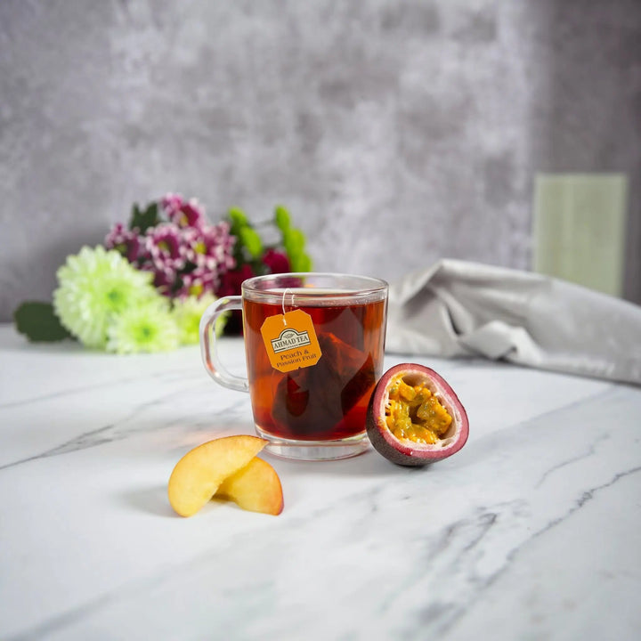 Delikatesi i tako to... Ahmad Tea Peach and Passion Fruit tea in a glass mug with fresh fruit slices on a marble table
