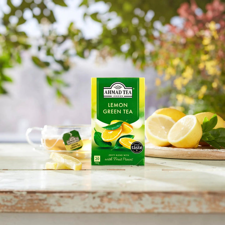 Delikatesi i tako to... Ahmad Tea Lemon Green tea box with fresh lemons and a cup of tea on a wooden table.