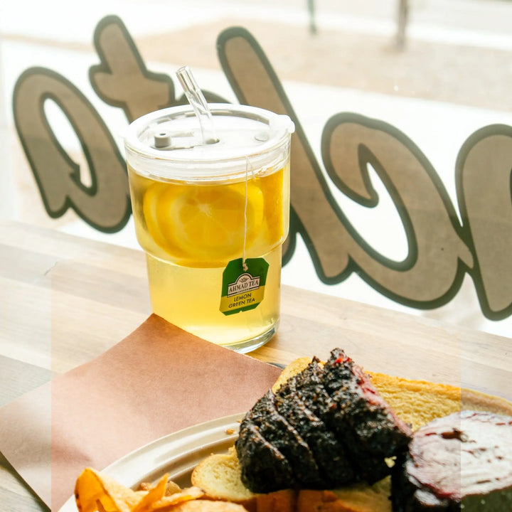 Delikatesi i tako to... Ahmad Lemon Green Tea served in a glass with lemon slices and a glass straw