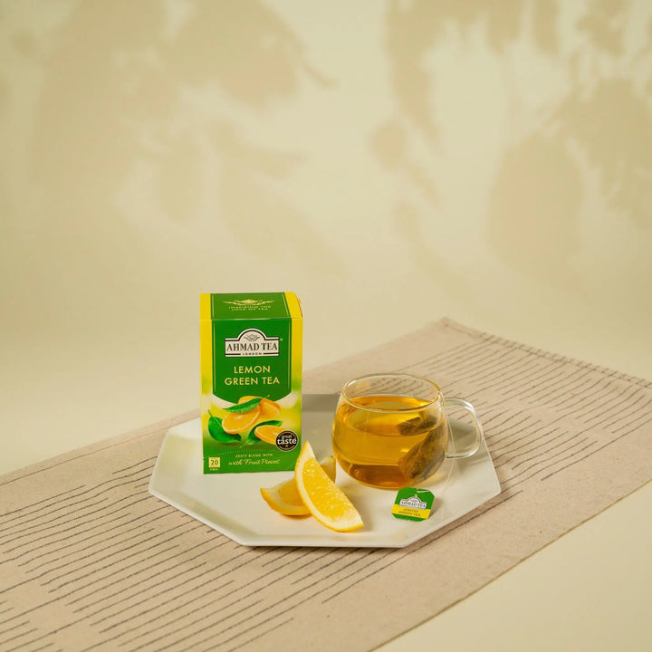 Delikatesi i tako to... Ahmad Tea Lemon Green tea box with a glass cup of brewed tea and fresh lemon slices.
