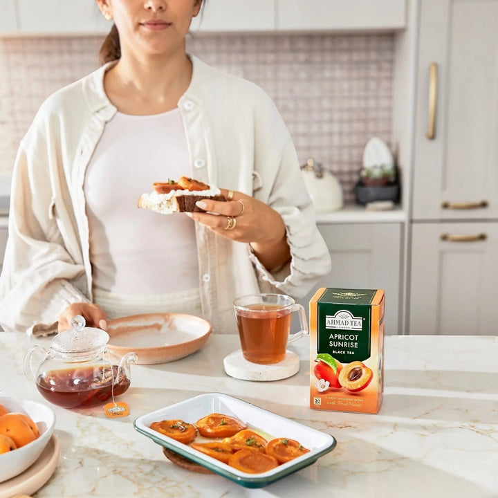 Delikatesi i tako to... Ahmad Tea Apricot Sunrise black tea box with a cup of tea and fresh apricots on a kitchen table