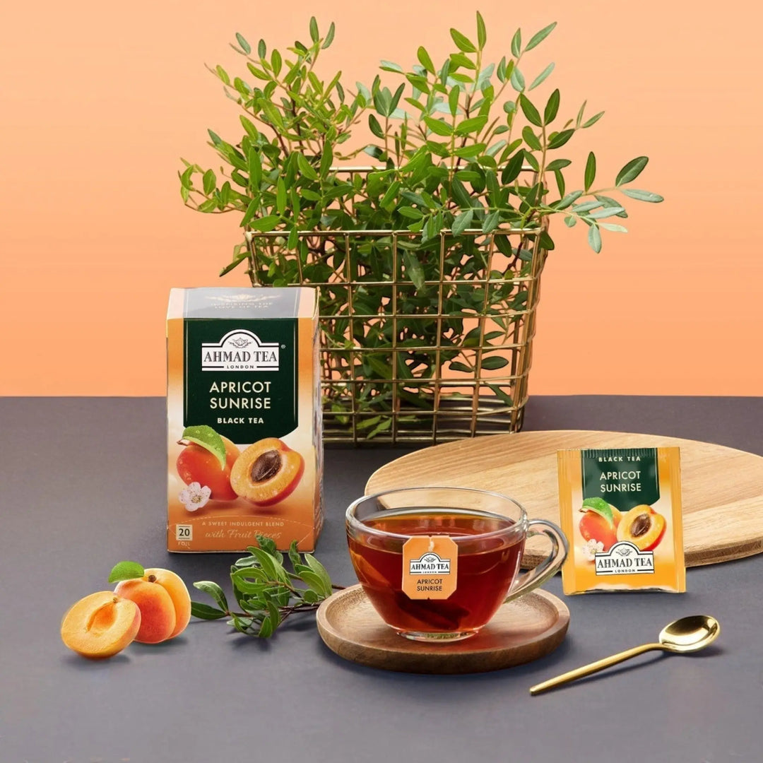 Delikatesi i tako to... Ahmad Tea Apricot Sunrise black tea box and cup with fresh apricots on a wooden table