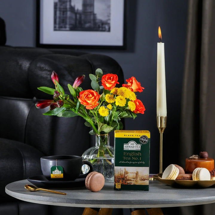Delikatesi i tako to... Ahmad Tea English Tea No1 box with tea cup, flowers, and macarons on a table