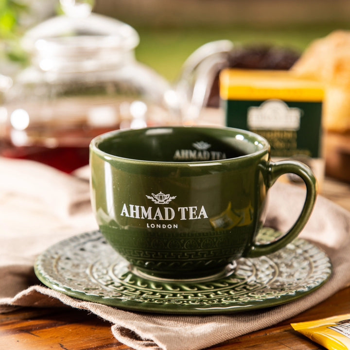 Delikatesi i tako to... branded Ahmad Tea green ceramic cup and saucer on a wooden table with tea box in background
