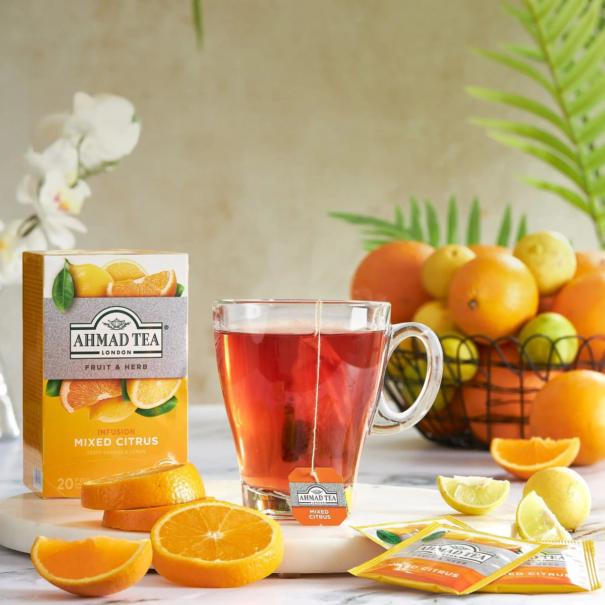 Ahmad Tea Mixed Citrus infusion box and glass cup of red tea by Delikatesi i tako to... with fresh orange slices