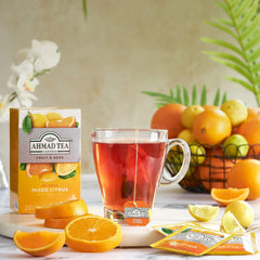 Ahmad Tea Mixed Citrus infusion box and glass cup of red tea by Delikatesi i tako to... with fresh orange slices