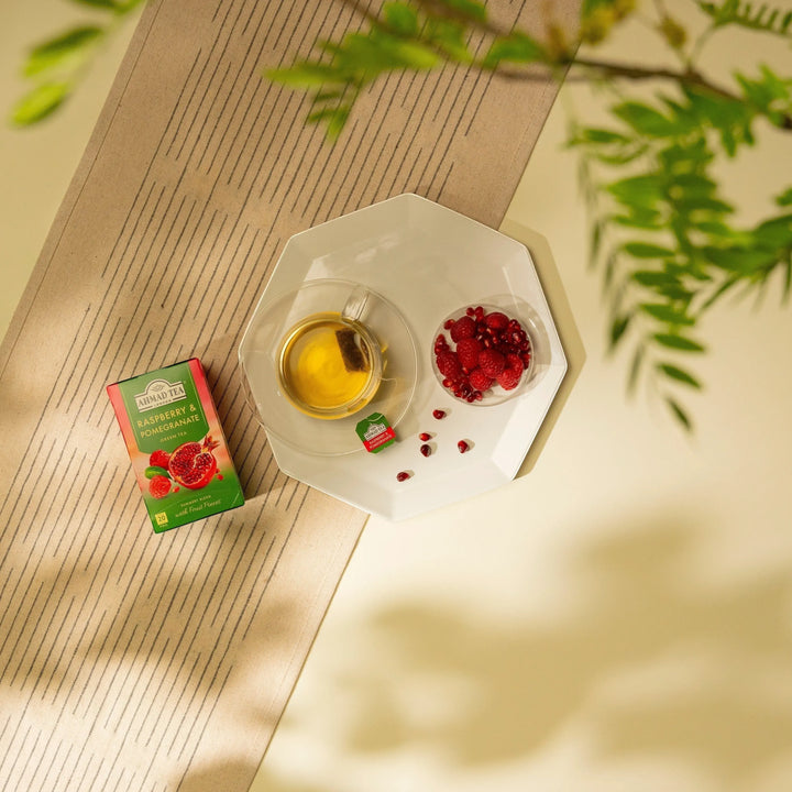 Delikatesi i tako to... Ahmad Tea Raspberry and Pomegranate green tea box with a cup of tea and fresh fruit