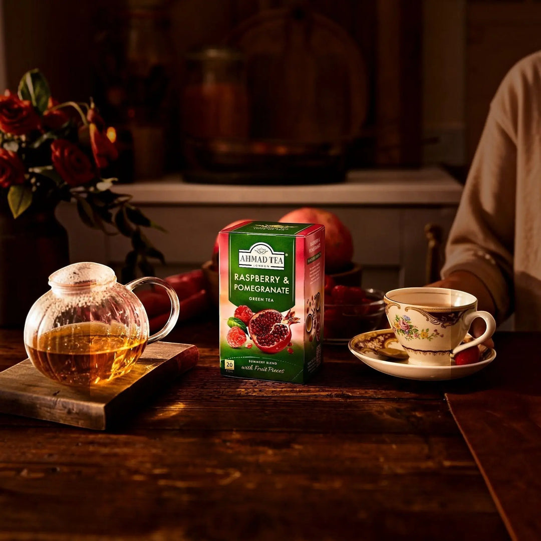 Ahmad Tea Raspberry & Pomegranate green tea box from Delikatesi i tako to... on a rustic wooden table with teaware.