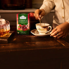 Delikatesi i tako to... Ahmad Tea Raspberry and Pomegranate green tea box next to a floral teacup being stirred