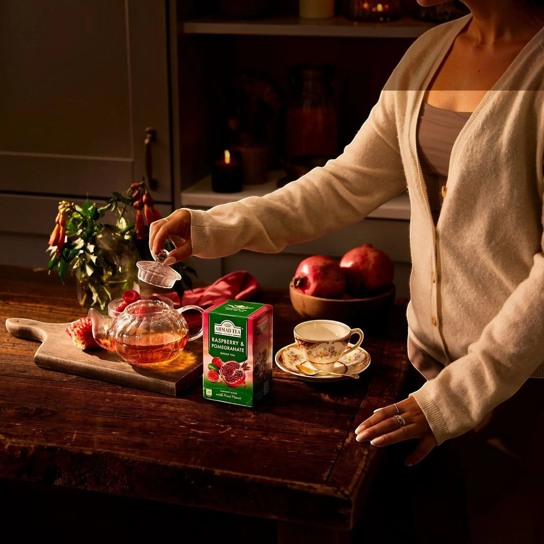 Delikatesi i tako to... Ahmad Tea Raspberry and Pomegranate green tea box with glass teapot and cup on wooden table