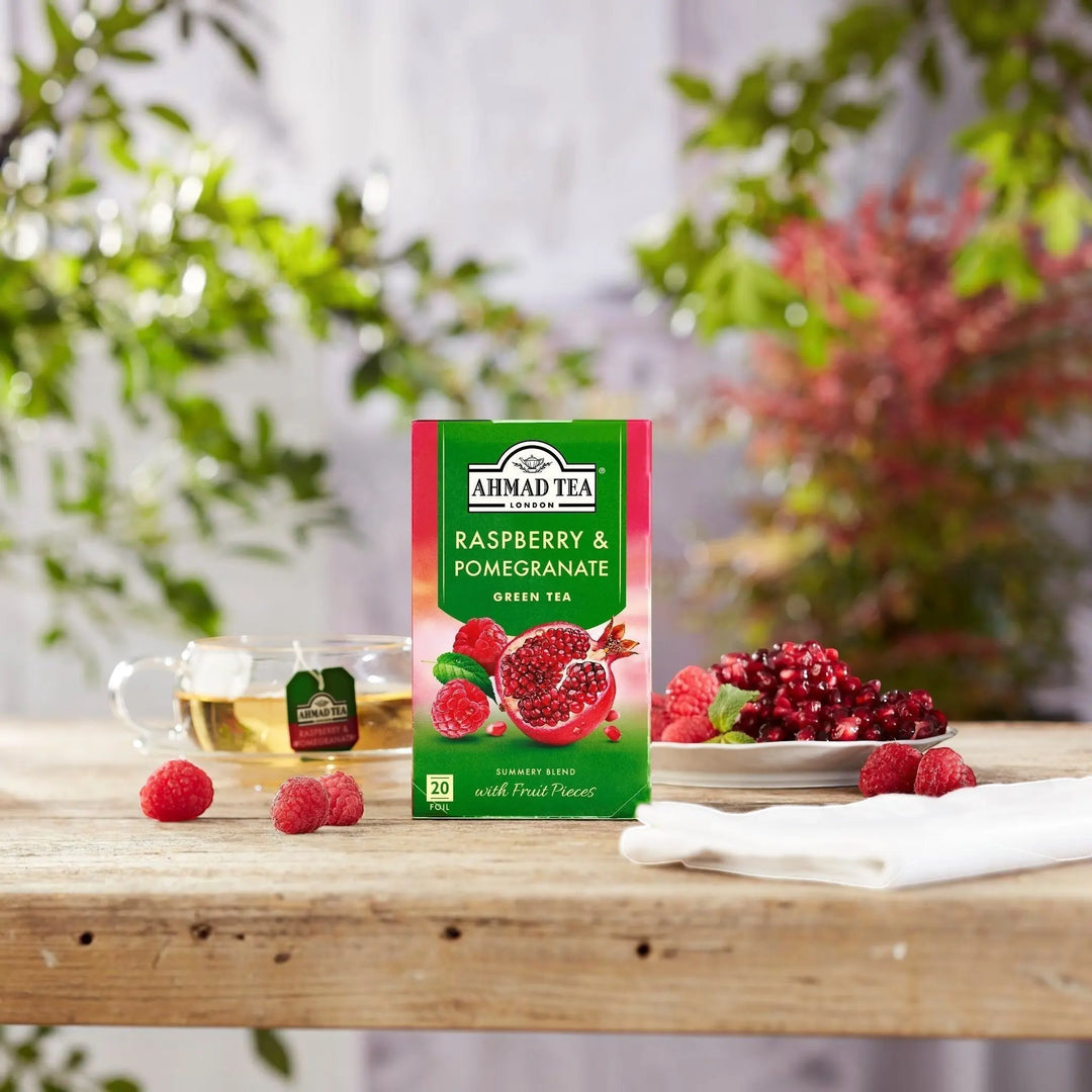 Delikatesi i tako to... Ahmad Tea Raspberry and Pomegranate green tea box with fresh fruit on a wooden table