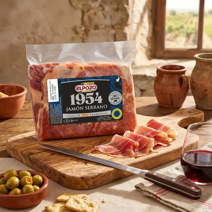 Delikatesi i tako to... ElPozo 1954 Serrano ham block with thinly sliced pieces on a wooden board with wine and olives.