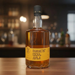 Delikatesi i tako to... Manastir Kovilj plum brandy in a 0.7l glass bottle with a yellow label on a wooden bar.