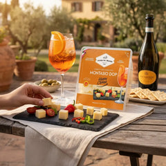 Delikatesi i tako to... Fior di Maso Montasio DOP cheese cubes served on a slate board with tomatoes and Prosecco