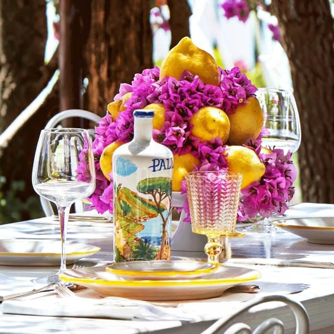Delikatesi i tako to... Pallini Limoncello bottle with Amalfi coast illustration, surrounded by lemons and flowers.
