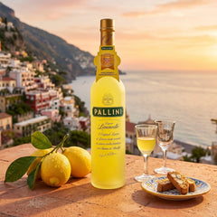 Delikatesi i tako to... Pallini Limoncello bottle with fresh lemons and biscotti on an Amalfi coast terrace at sunset