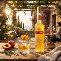 Delikatesi i tako to... Pallini Peachcello peach liqueur bottle with a cocktail on a rustic outdoor table at sunset