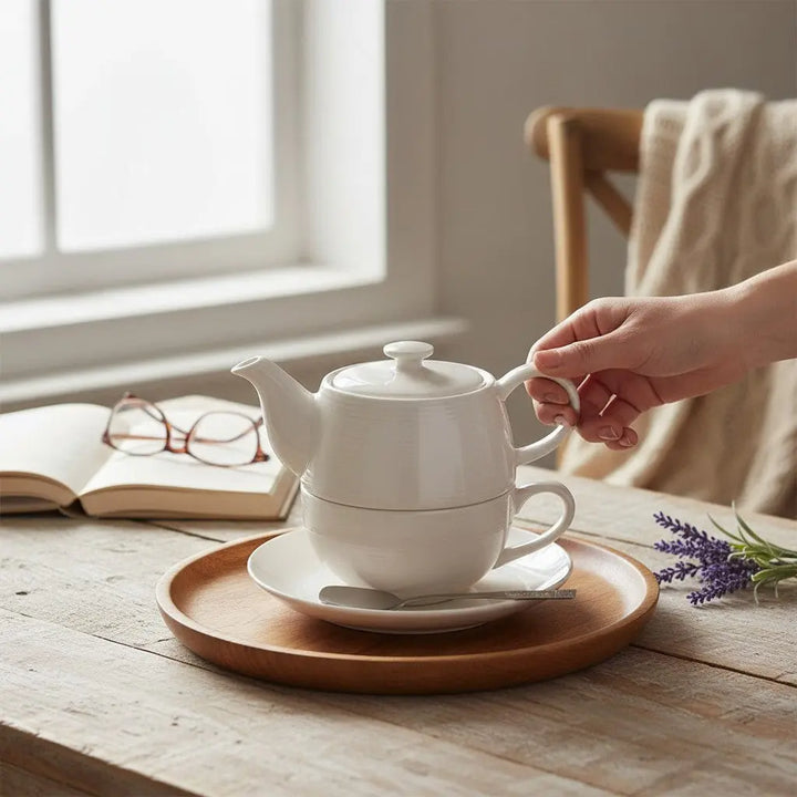 Delikatesi i tako to... Ahmad Tea white ceramic solo tea set with teapot, cup, and saucer on a wooden tray.